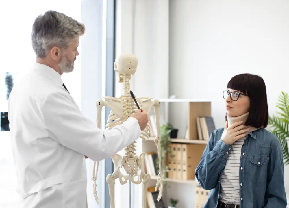 A doctor giving medical advice to a female patient wearing a neck brace in an exam room.