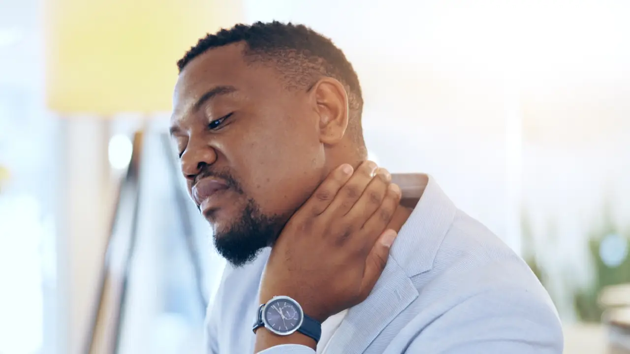A man holding his neck in pain due to a neck injury.