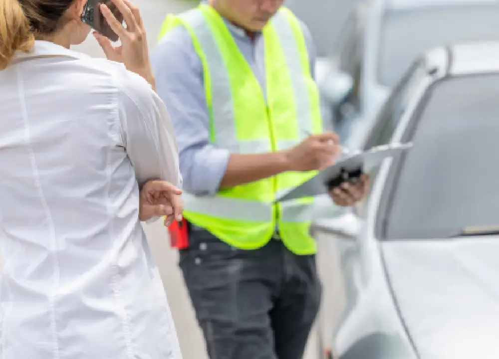 Police officer taking notes at the scene of a car accident, documenting details.
