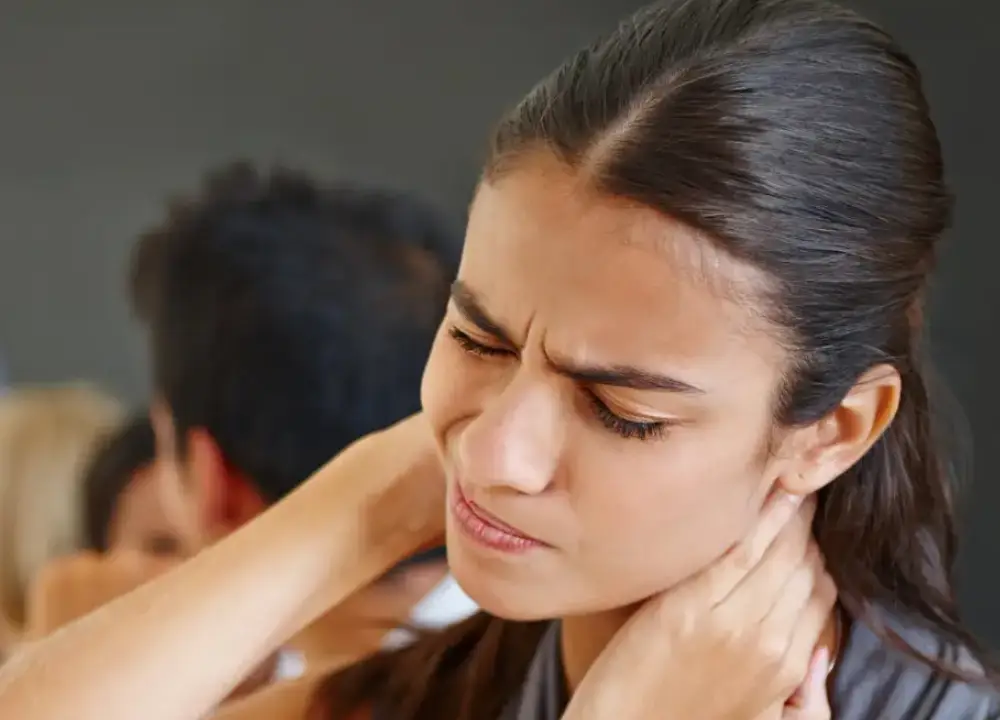 Person clutching neck, showing pain from whiplash injury