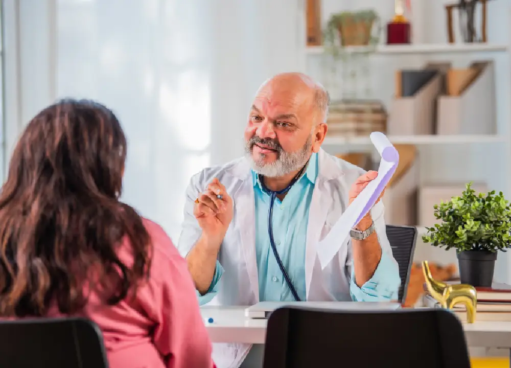 A woman patient visiting an elderly male doctor for a consultation in a clinic.